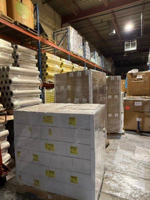 Warehouse racking stocked with film rolls and cased goods