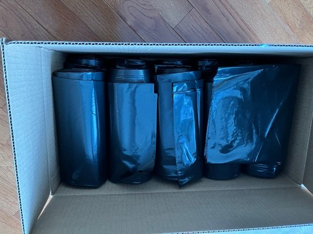 Case of black can liners packed on rolls