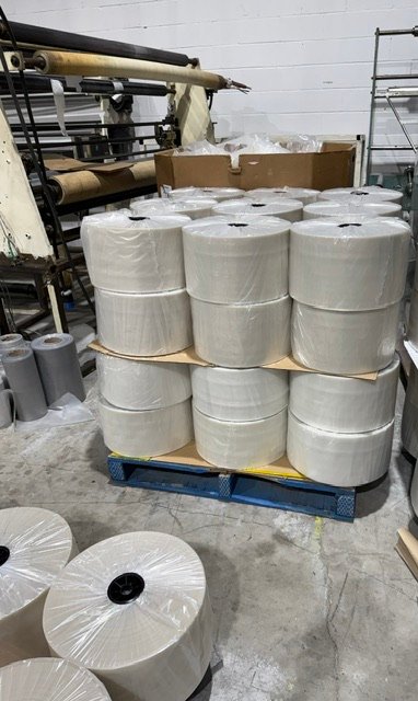 Pallet of natural poly film rolls beside converting equipment